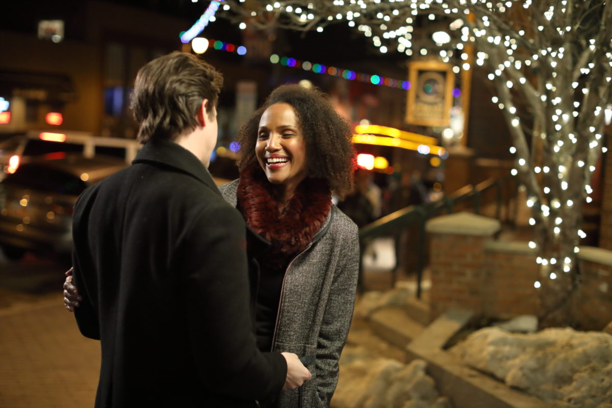 Couple embracing under Christmas lights on Main Street Park City