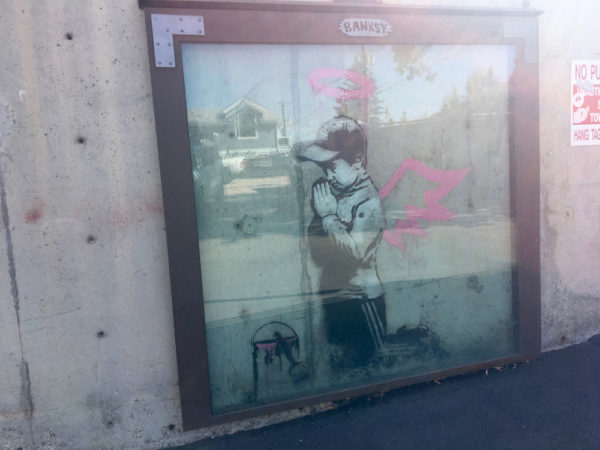 Banksy praying boy with pink halo