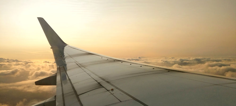 Wing of Plane in Flight Over Clouds