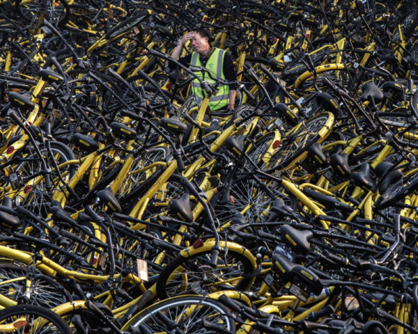 Man overwhelmed by stacks of discarded bikes