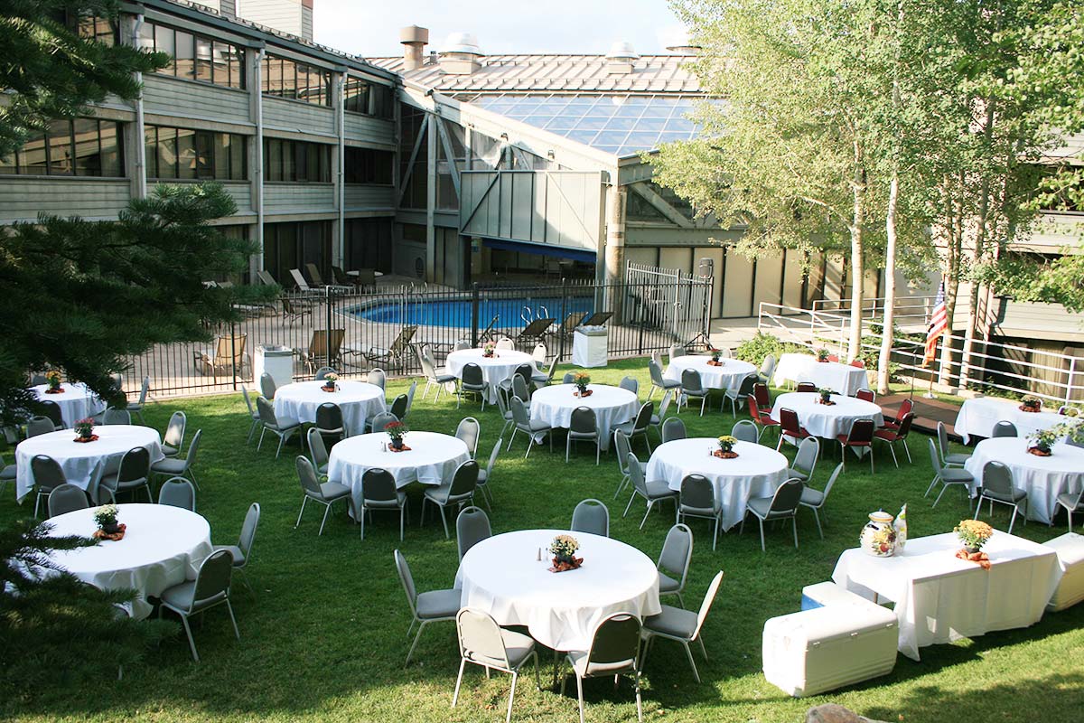 twelve round white tables set up in a green lawn for an outdoor event