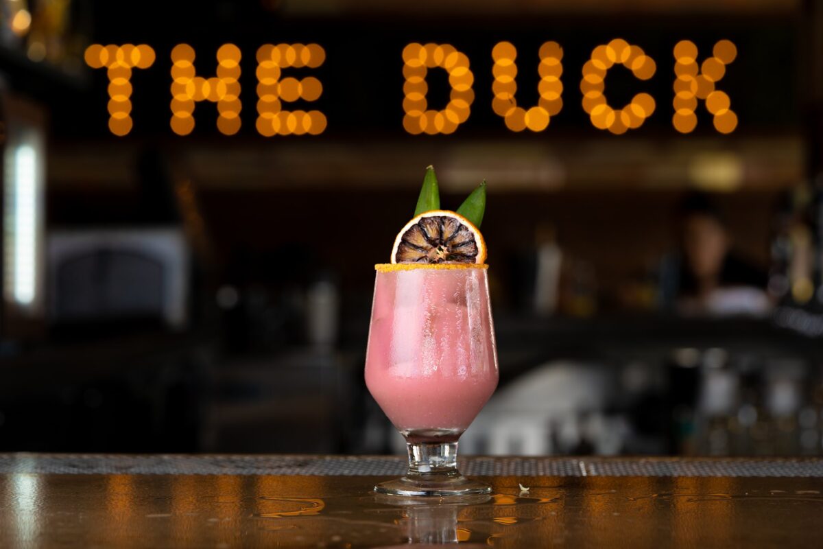 cocktail-in-front-of-The-Duck-Dive-Marquee-Sign-1200x800