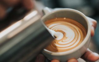 Barista Pouring Milk into Coffee Cup