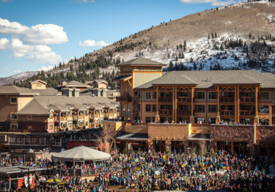 Aerial View of Sundial Lodge in Early Spring with Crowd of People at the Mountain Base Area of Canyons Village
