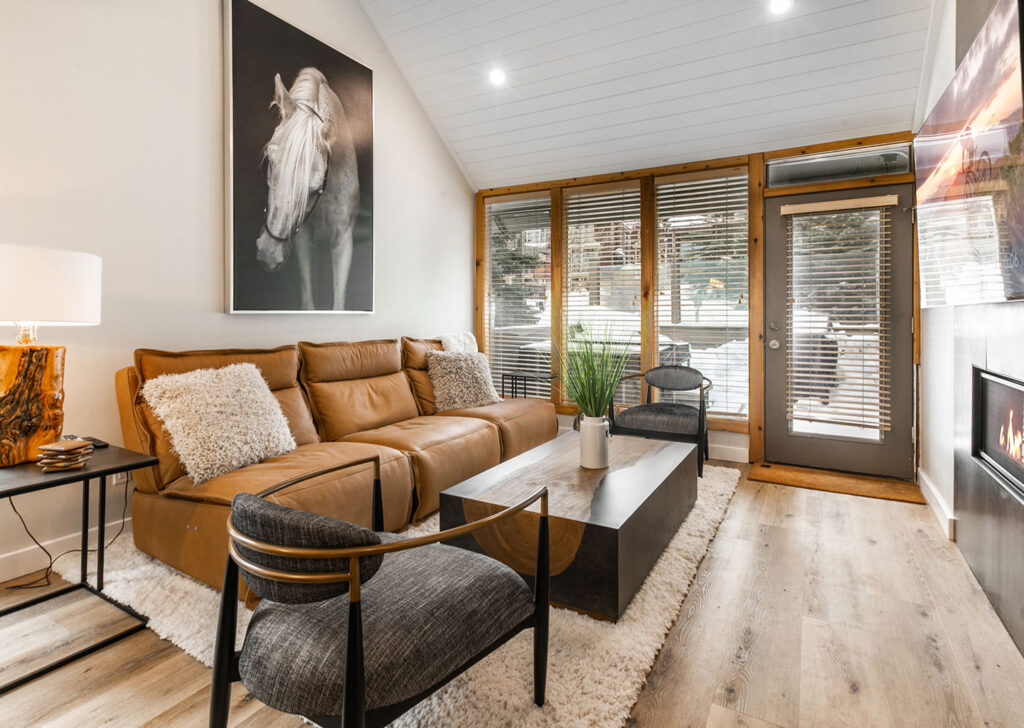 downstairs living area with large windows and a patio with a hot tub