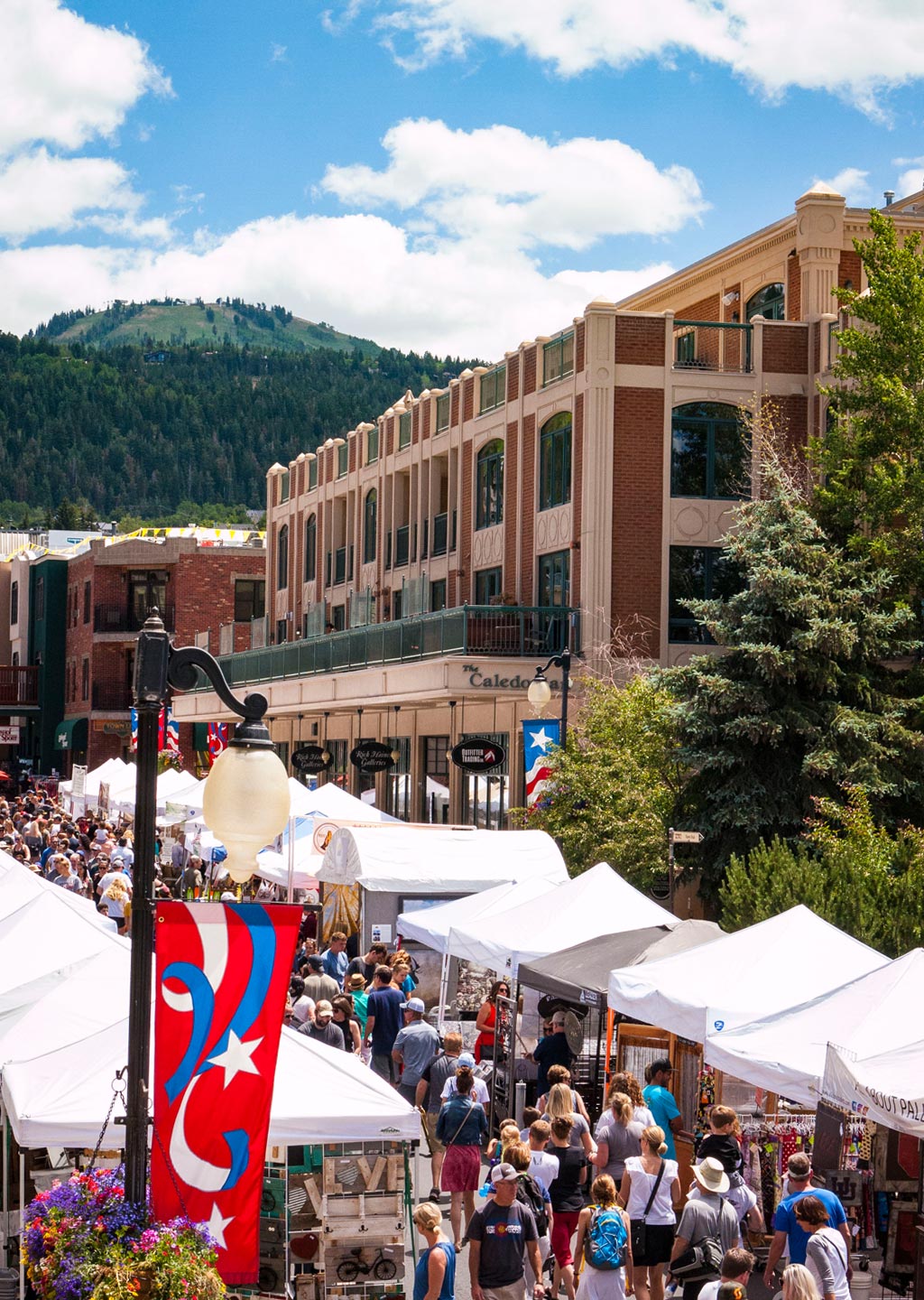 Park Silly Sunday festival on Main Street Park City during summer time. The Caledonian Hotel in the mid-ground, Deer Valley rises in the background