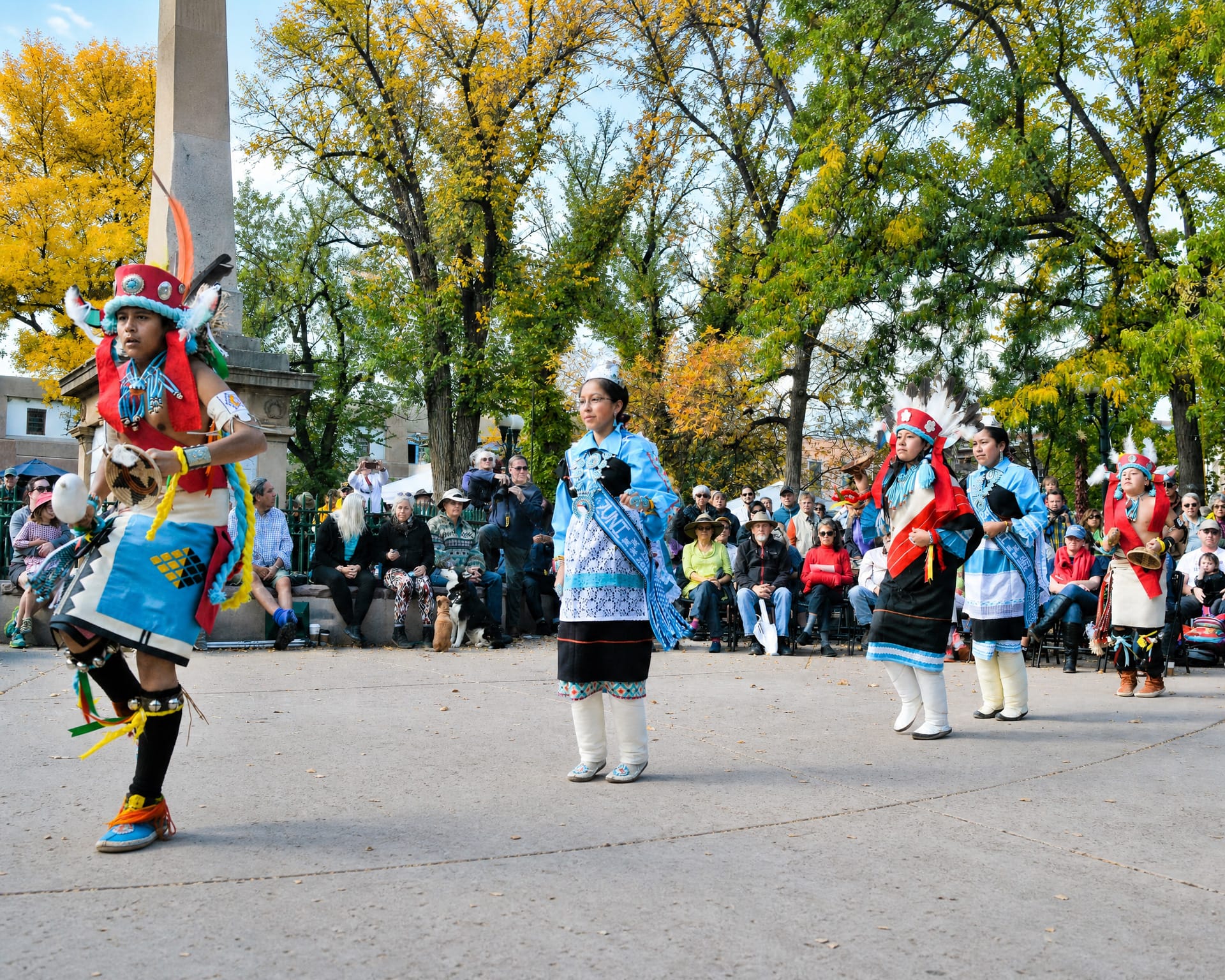 Native American dancers in traditional regalia performing on the Santa Fe Plaza during Indigenous Peoples' Day